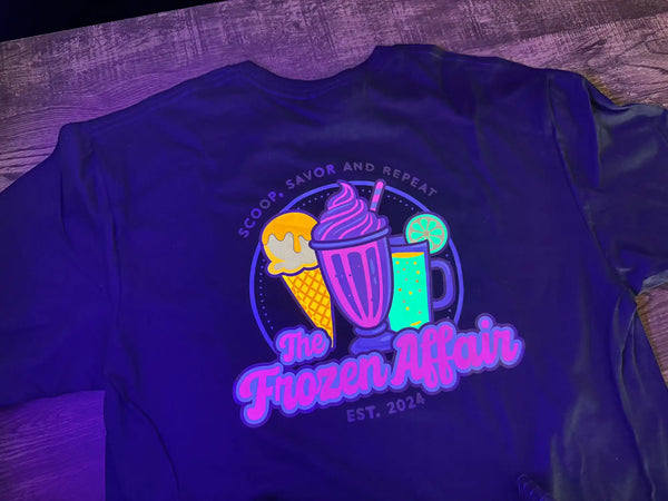 A black t-shirt with a colorful, glowing graphic of ice cream, a milkshake, and a beverage, with the words ’The Frozen Affair’ and ’EST. 2024’’ and ’SCOOP, SAVOR AND REPEAT’ on it.