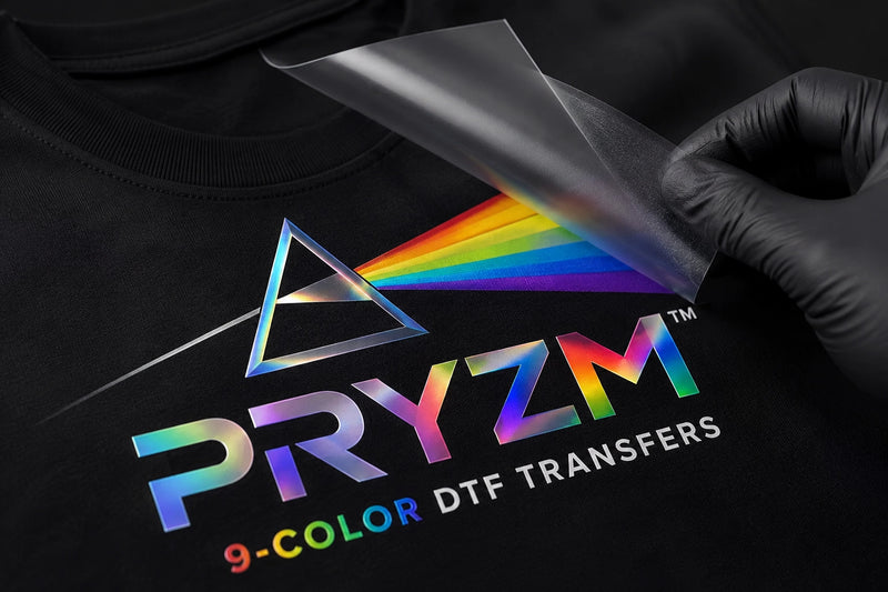 Close-up of a PRYZM™ 9-Color DTF Transfer being peeled from transfer film, showcasing advanced RGBO extended gamut printing technology, ultra vivid colors, smoother gradients, enhanced color fidelity, premium heat transfers, and photo-real apparel decoration by MAYA TX.