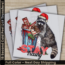 Load image into Gallery viewer, a raccoon wearing a santa hat and holding a candy bar
