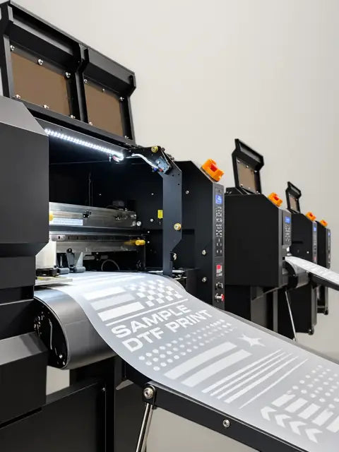 Row of DTF printers feeding white-ink test prints on transfer film